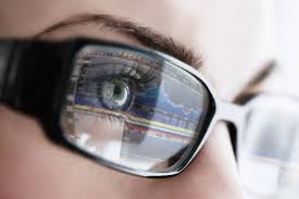 Close-up of a person's eye wearing glasses, reflecting digital eye exam data, emphasizing the importance of vision care and optical services.